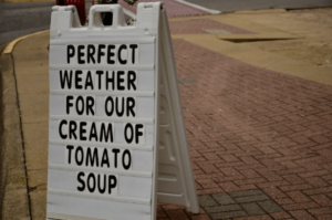 A sign that says " perfect weather for our cream of tomato soup ".