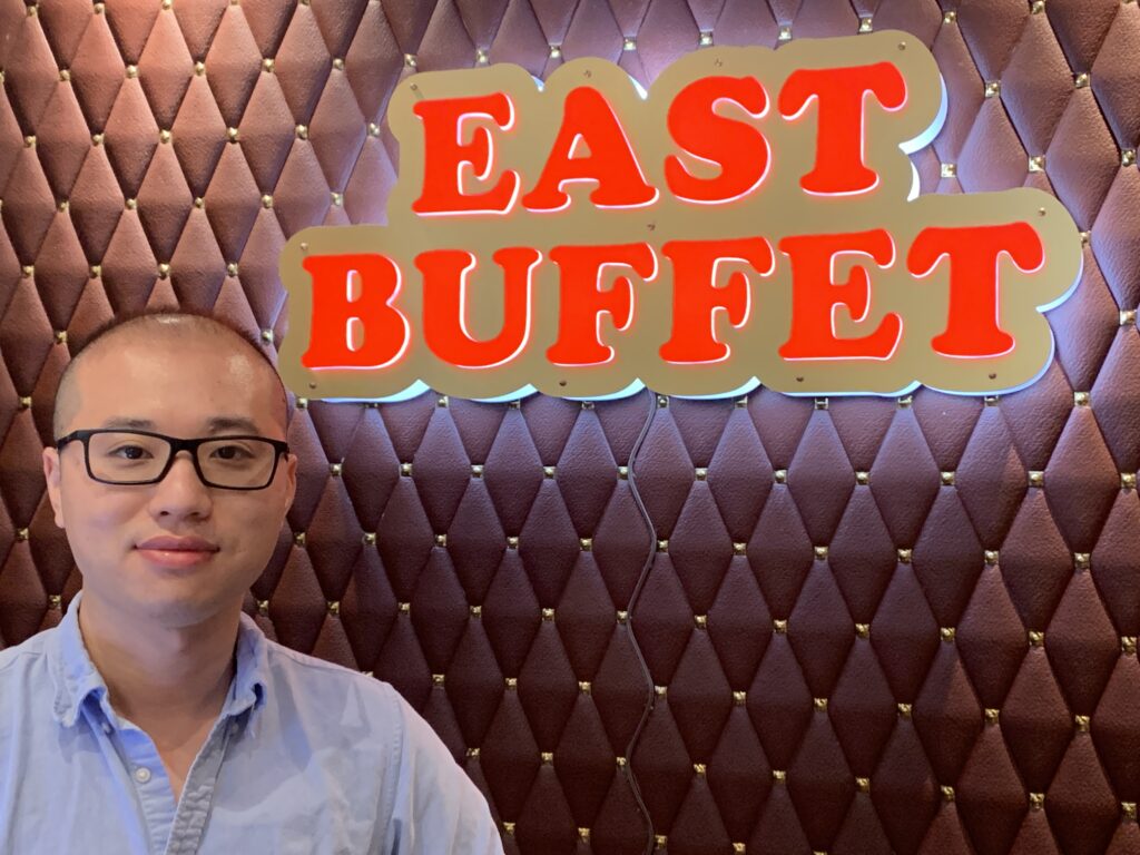 A man standing in front of the east buffet sign.