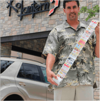 Man holding long receipt outside a building.