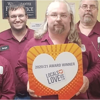 Group holding award sign, smiling together.