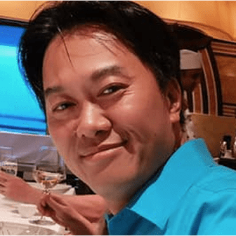 Smiling person in a blue shirt dining.