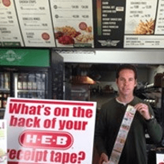 Man holding receipt tape in store.