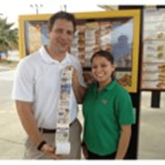 Two people holding long receipt outdoors.