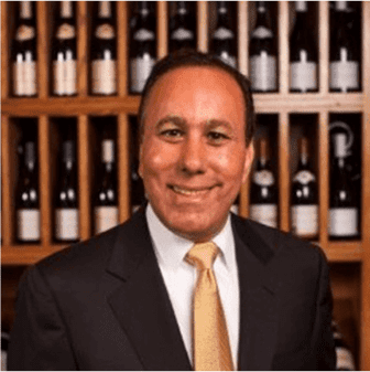 Man in suit with wine bottles background.