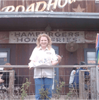 Person standing outside rustic burger restaurant.