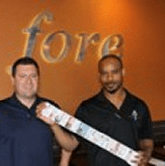 Two men holding a long object indoors.