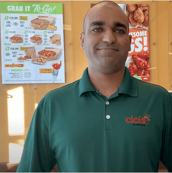 Man in green shirt at restaurant counter.